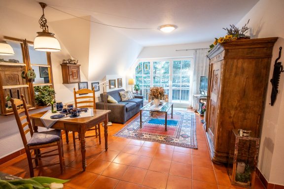 Helle, einladende Wohnküche mit Esstisch, gemütlicher Sitzecke und großen Fenstern.