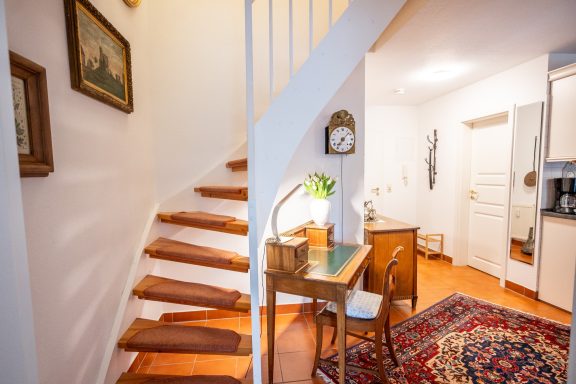 Treppenhaus mit Holzstufen, Tischlampe und Schreibtisch in einem einladenden Raum.