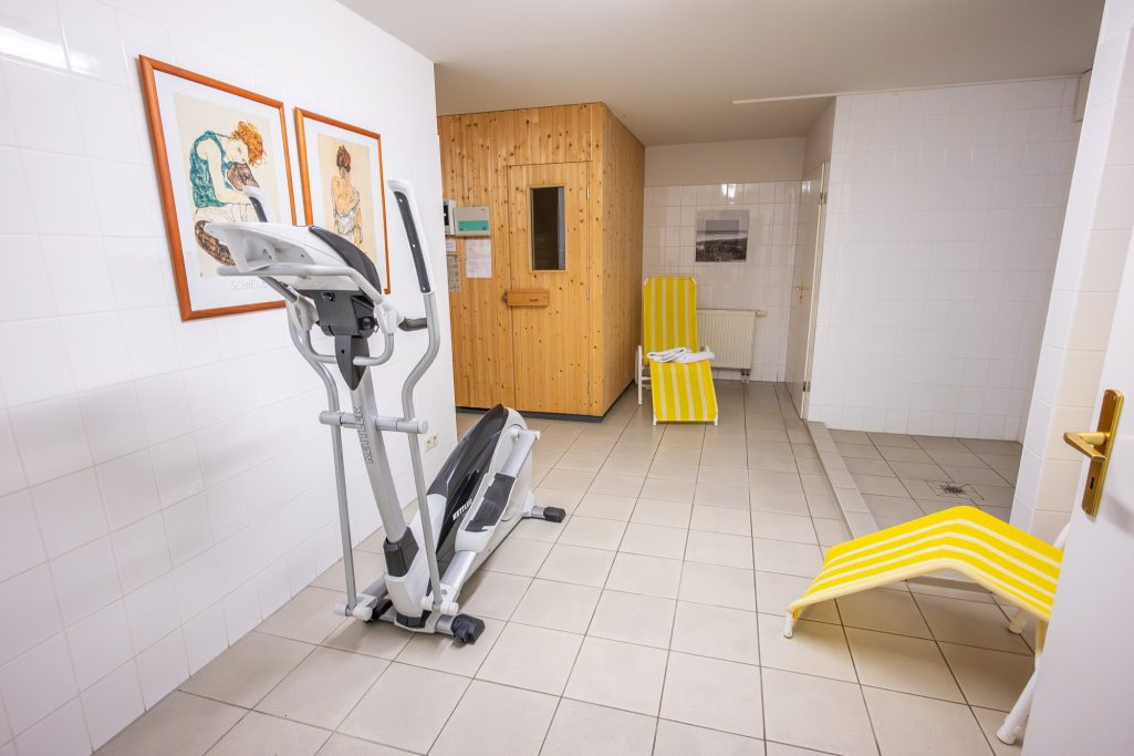 Großzügiger Saunabereich im Keller mit Sauna, Dusche, Ruheliegen und zusätzlichem Stepper für leichte Aktivität vor oder nach dem Saunagang.