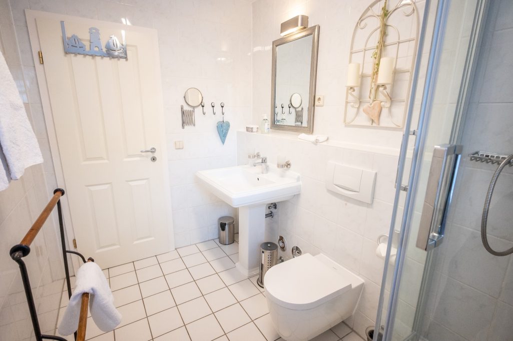 Modernes Bad mit Dusche und Glaskabine, Waschbecken, WC, Föhn, Kosmetikspiegel und Fenster. Fliegengitter sorgen für angenehmes Lüften.